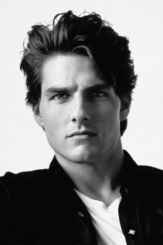 Black and white portrait of a young man with tousled hair, wearing a dark shirt and looking directly at the camera.