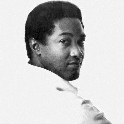 A black and white portrait of a man with short, curly hair looking over his shoulder, displaying a thoughtful expression.